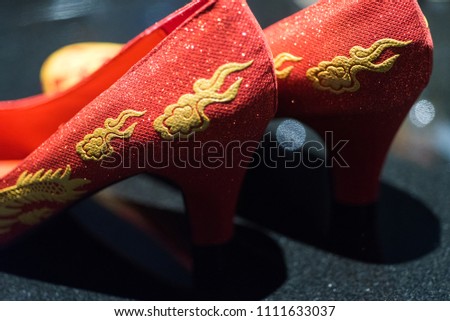 Traditional pair of red wedding shoes worn by Chinese bride as part of a "Qipao" outfit on wedding day. Te sign on shoes means happiness in wedding day and copy space.