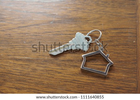 Home key with metal house keychain on wooden table, property concept