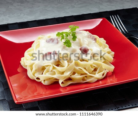 Bacon cream pasta on red plate