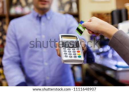 Photo of seller with terminal in hands and buyer with bank card.