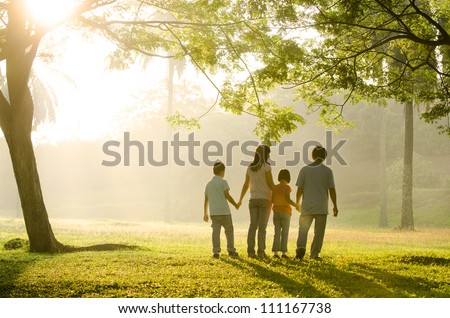 an asian family walking in the park during a beautiful sunrise, backlight