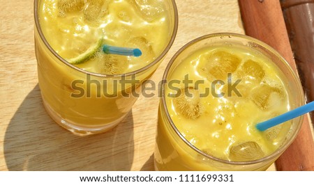 Fresh mango cocktail with ice cubes. Two glasses of refreshing drink on a wooden table. Top view. Refreshing drinks in summer time. Close up. Beautiful image. Food Photography