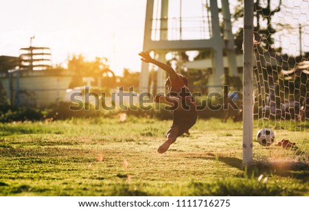 An action sport picture of a group of kid playing soccer football for exercise in community rural area under the sunset.