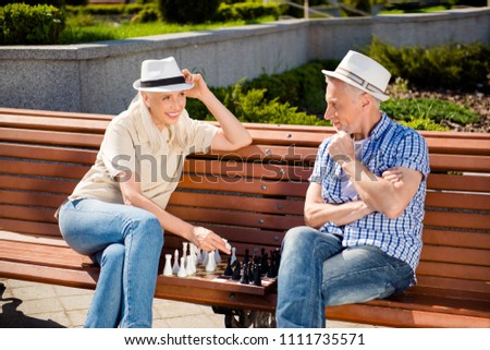 Portrait of romantic lovely couple in casual outfits playing chess in park sitting on bench enjoying vacation holiday together. Rest relax weekend concept