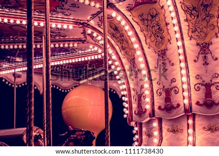Children's Carousel at an amusement park in the evening and night illumination. amusement park at night. Outdoor vintage colorful carousel in the the city. Vintage photo processing