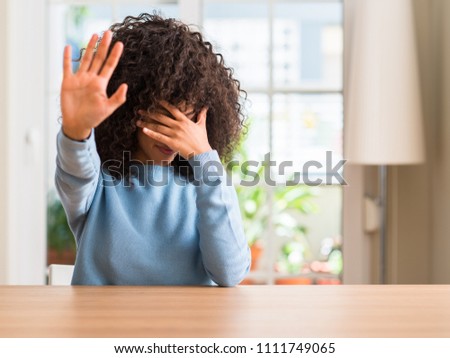 African american woman at home covering eyes with hands and doing stop gesture with sad and fear expression. Embarrassed and negative concept.