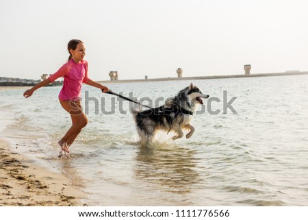 Young girl with alaskan malamute dog on the beach in Dubai 