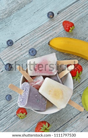 Homemade popsicle with strawberries, blueberries, apple and banana on a wooden background perfect for the summer as a refreshment