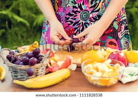 woman in the garden cuts fruit salad