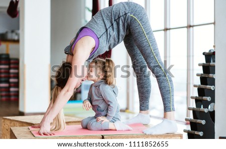 Mom and daughter together perform different exercises in the gym