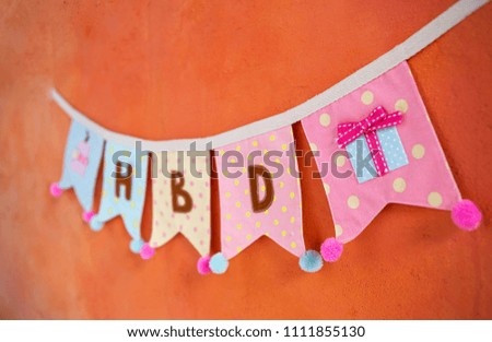 Colorful fabric birthday party flag hanging on orange cement wall, design birthday party decorate flag