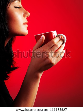 Beautiful lady drinking coffee, brunette enjoy cup of hot chocolate, side view cute girl isolated on red background, portrait of female with morning tea, gorgeous woman holding cappuccino mug Royalty-Free Stock Photo #111185627