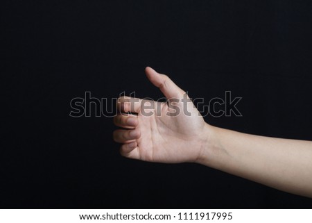 The gesture of a hand holding a phone on black background, isolated                               