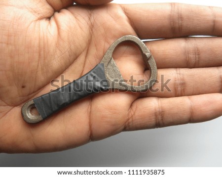 Small metal bottle opener on palm of hand