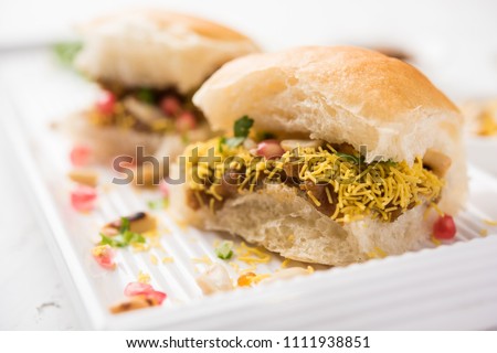 Dabeli is an Indian snack item served with Pomegranate Seeds and Cilantro in white ceramic plate. It's a popular Navratri Festival food
