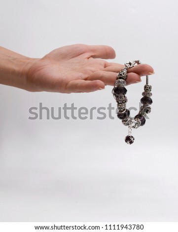 A stainless bracelet.  Luxury silver bracelets in women hand on white background. Violet bracelets in hand