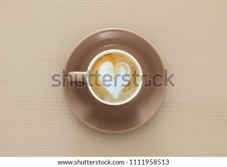 image of coffe cup with foam of heart shape over wooden table