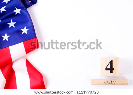 Ruffled American flag and wooden cube calendar with 4th of July date. Happy Independence Day greeting card template on white copy space background. US patriotic festive composition, top view, close up