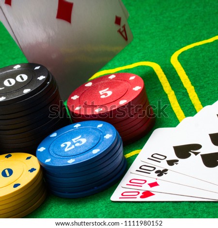 multicolored poker chips behind which falls a diamond ace against a background of bright green canvas concept of board games and casino