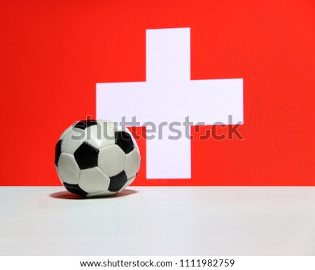 Small football on the white floor with white cross on red color of Swiss nation flag background. The concept of sport.