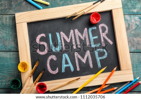 Text "SUMMER CAMP" on chalkboard, brushes and paints, top view