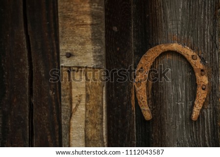 Lucky rusty old horseshoe hanging in the barn. Rusty horseshoe on an old and abandoned farm wooden house