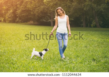 Beautiful woman enjoys walking with her  cute dog Jack Russell Terrier in the nature.Image is intentionally toned.