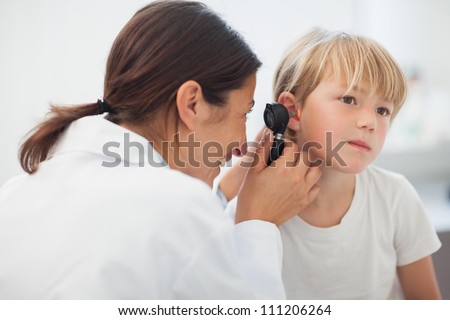 Doctor auscultating the ear of a child in examination room Royalty-Free Stock Photo #111206264