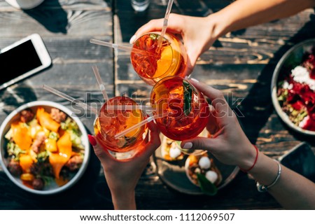 Friends toasting each other with aperol spritz cocktails at the dinner table, top view Royalty-Free Stock Photo #1112069507
