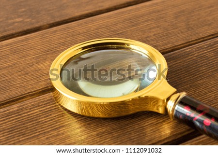 Magnifying glass on wooden table. Search concept.
