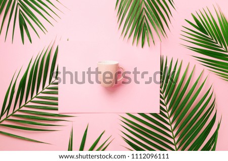 Tropical palm leaves on pastel pink background with paper card note, cup. Minimal summer concept. Creative layout. Top view, flat lay. Green leaf on punchy pastel paper.