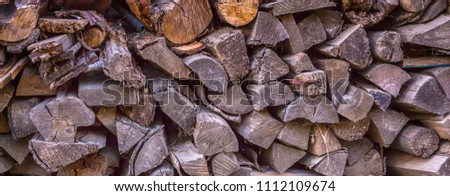 stack of firewood stacked for a stove and a fireplace near the house in rustic rustic style background with space for text long banner