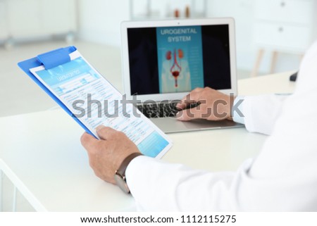 Mature urologist working at table in hospital