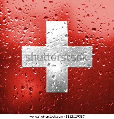 Texture of Switzerland  flag on the glass with drops of rain. 