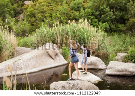 Cute young couple crossing river. Camping season