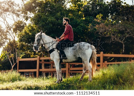 Young man riding white horse on the countryside