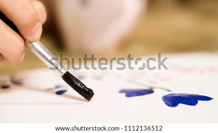 Closeup of child hand carefully drawing flowers with gouache, creativity, talent
