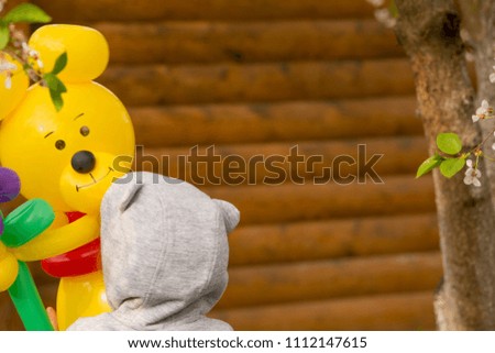 little girl holding large yellow bear from balloons