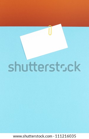 Business card attached on a blue sheet with a yellow clip