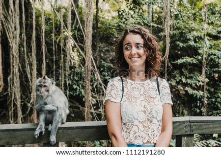 Scared funny woman taking some pictures with a cute monckey in the monckey forest in Ubud, Bali. Lifestyle. Travel photography