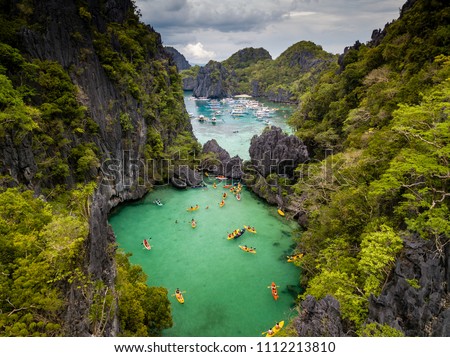 Aerial drone view of a beautiful tropical lagoon filled with kayaks and surrounded by jagged limestone cliffs (Small Lagoon, Miniloc Island, El Nido) Royalty-Free Stock Photo #1112213810
