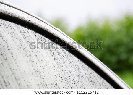 Drops of water on the car after rain with blurred nature for background.