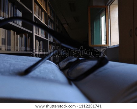 A book and glasses with heart-shaped leaves on the desktop.Rear-panel library, books.