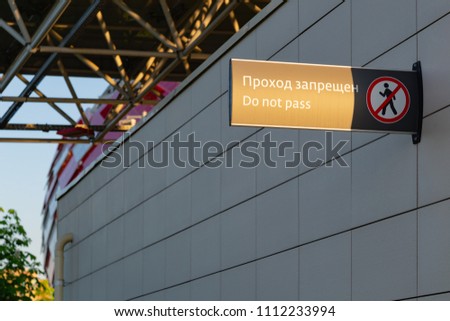 Sign panel with prohibition icon and inscription - Pass is forbidden "Do not pass" on the wall of a building near the stadium. Horizontal.