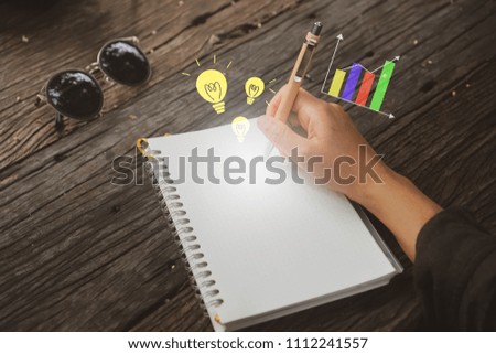 Copy space of woman hand writing down in white notebook with idea and graph icon  background. 