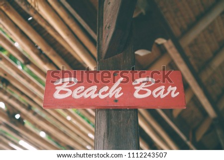 Beach bar word on wood board hang on the wooden pole.