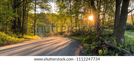 The sun rises over a dirt road in Vermont in the early springtime.