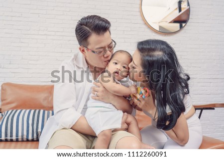 Asian Happiness family scene of parent are kissing the boy baby in the living room of house,Family Lifestyle Concept