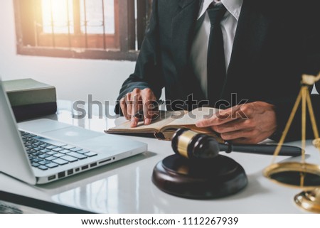Male lawyer working with legal book and white desk table with laptop,gavel,scale.justice and law concept.