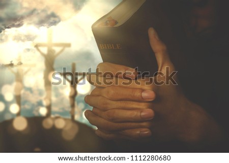 Picture of christian person holding a bible with crucifixion sign on the background